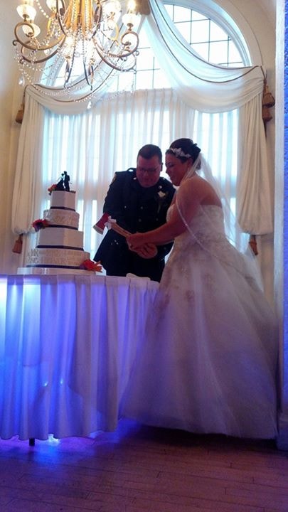 Bride and groom cutting their wedding cake beneath a chandelier