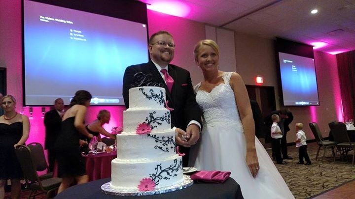 Bride and groom beside a decorated wedding cake at their reception