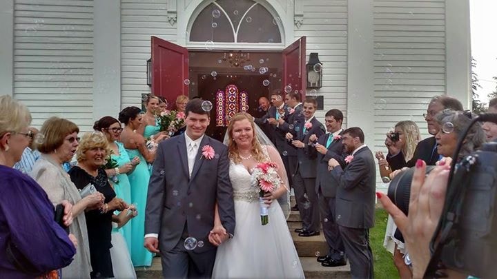 Newlywed couple leaving a church surrounded by wedding guests