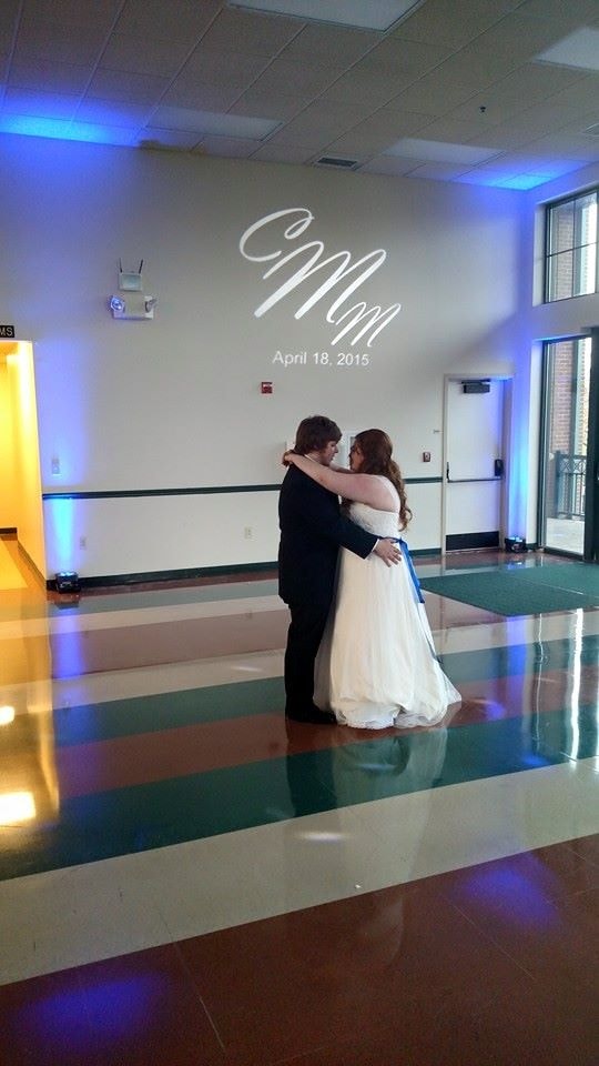 Newlyweds sharing a first dance beneath a custom monogram projection