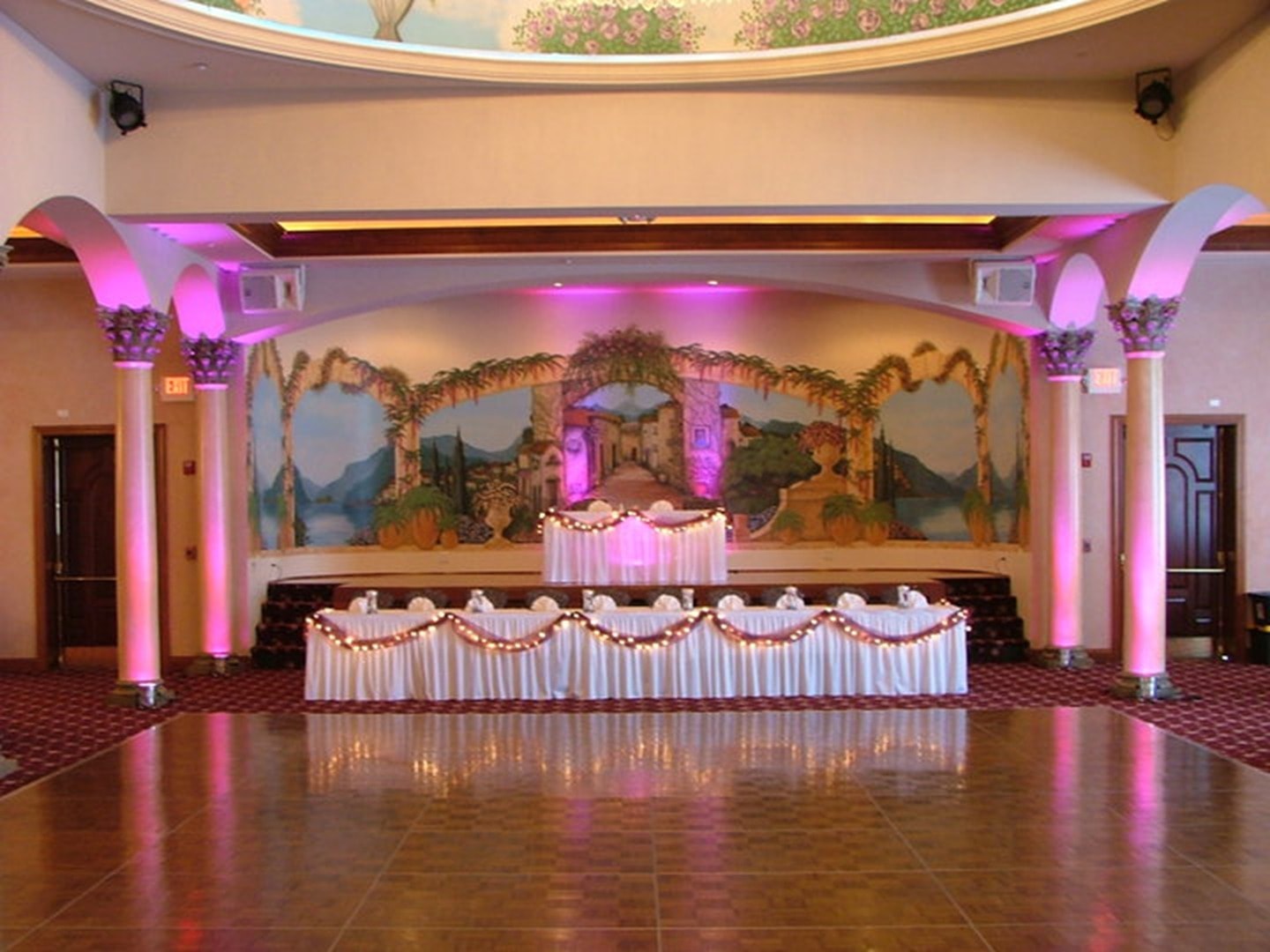 Ballroom reception set with pink uplighting and a polished dance floor